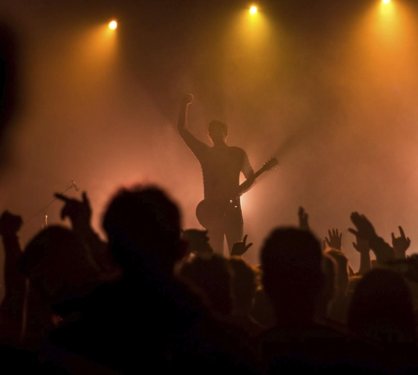 artista tocando la guitarra en escenario con público