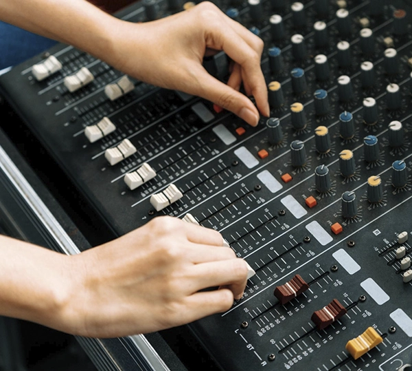 manos manejando mesa de sonido